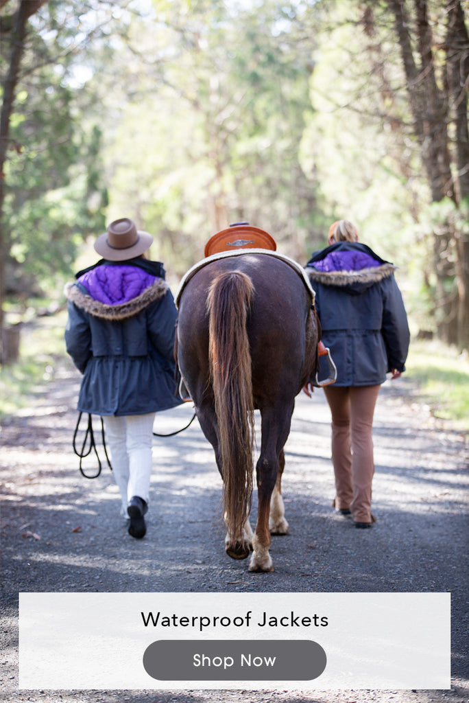 Image of two woman walking next to a horse with waterproof horse riding jackets on